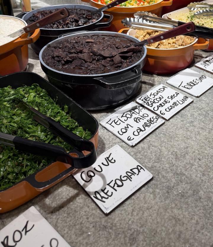 Panela de feijoada com paio e calabresa ao lado da couve refogada